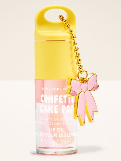Olej na rty Bath & Body Works Confetti Cake Pop 2,5 g v pastelovém obalu s ozdobným přívěskem mašle.