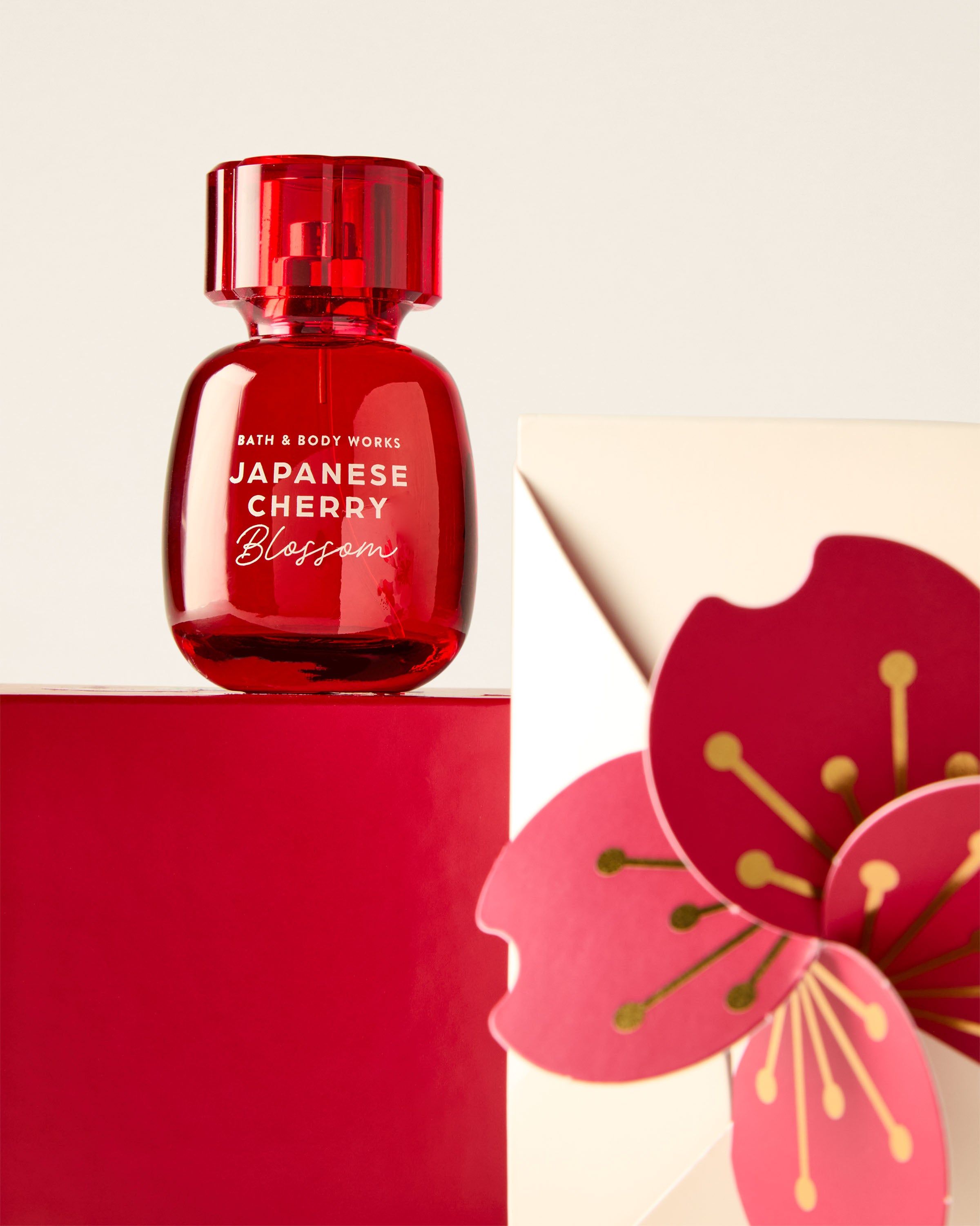 Červená parfémová voda Bath & Body Works Japanese Cherry Blossom na červeném podstavci s květinovým motivem