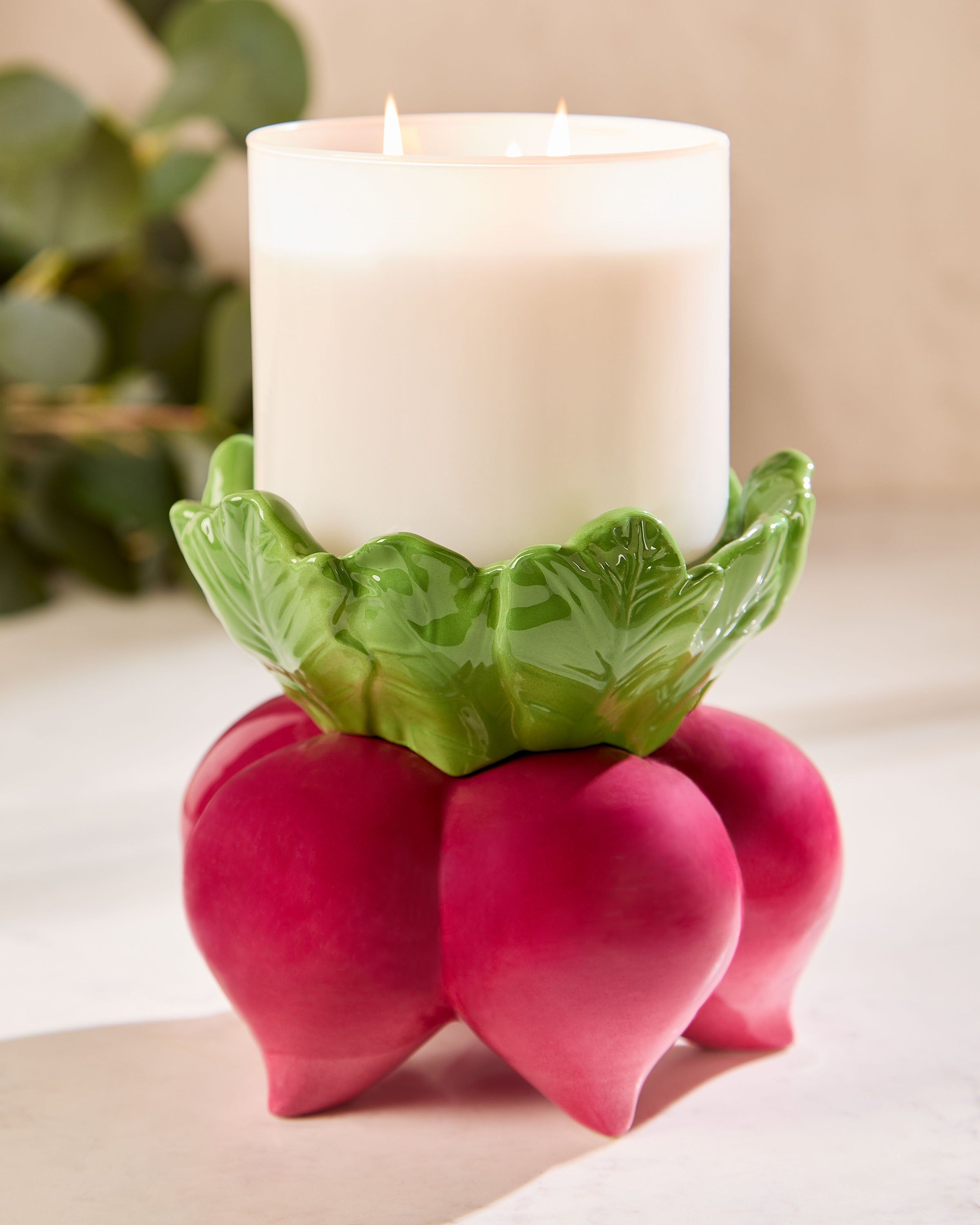 Dekorativní podstavec na tříknotovou svíčku Bath & Body Works ve tvaru řepy se zelenými listy.