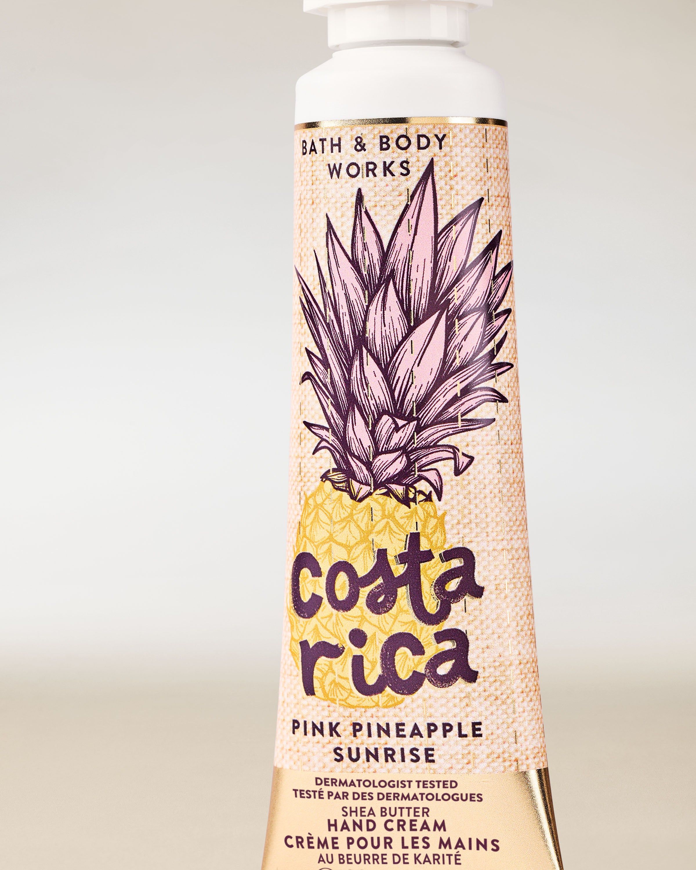 Krém na ruce Costa Rica Pink Pineapple Sunrise ve žluté tubě s ananasovou ilustrací a tropickým motivem.