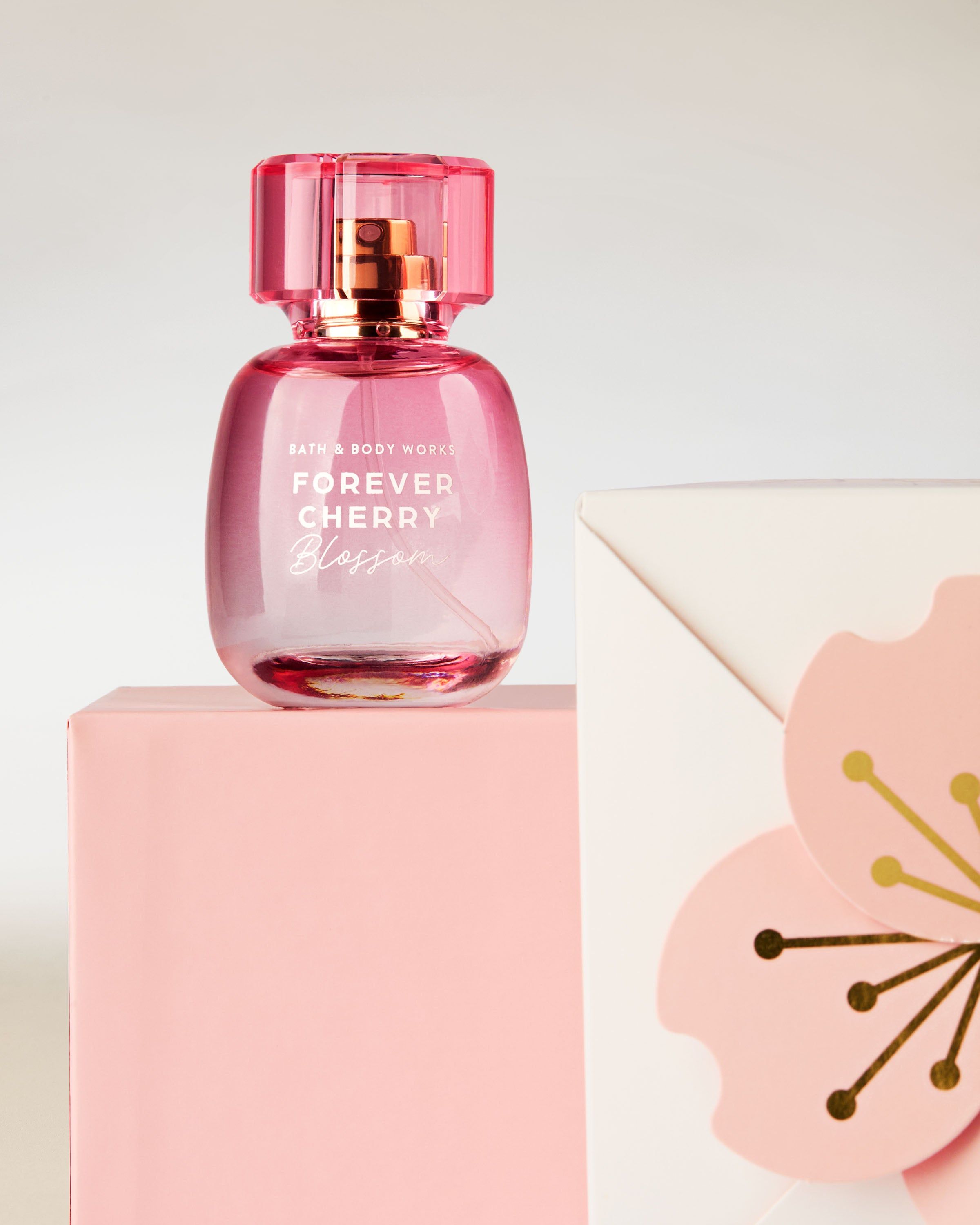 Parfém Bath & Body Works Forever Cherry Blossom v růžovém flakonu na pozadí třešňových květů.