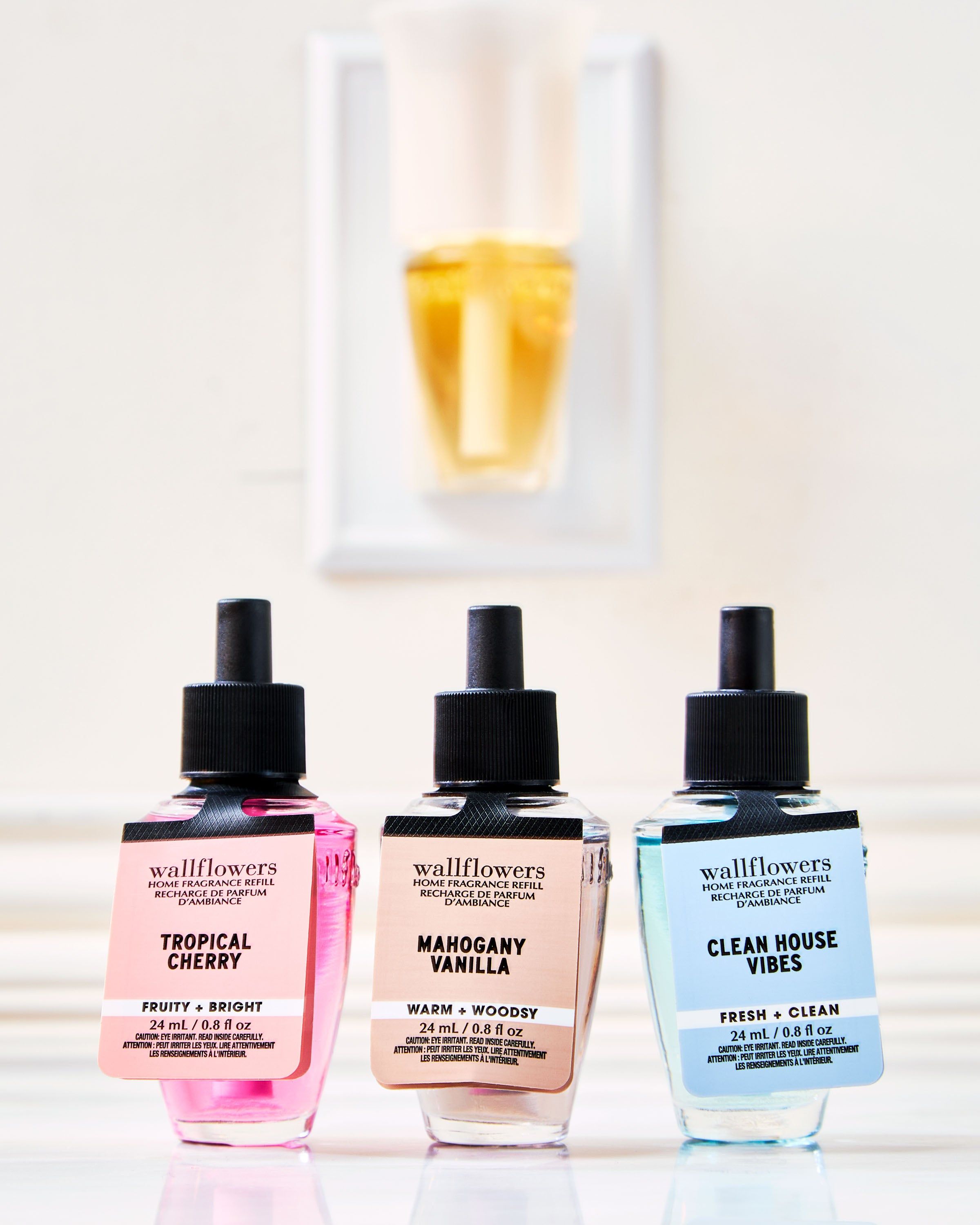 Trojice náplní Wallflowers: Tropical Cherry, Mahogany Vanilla a Clean House Vibes před difuzérem.