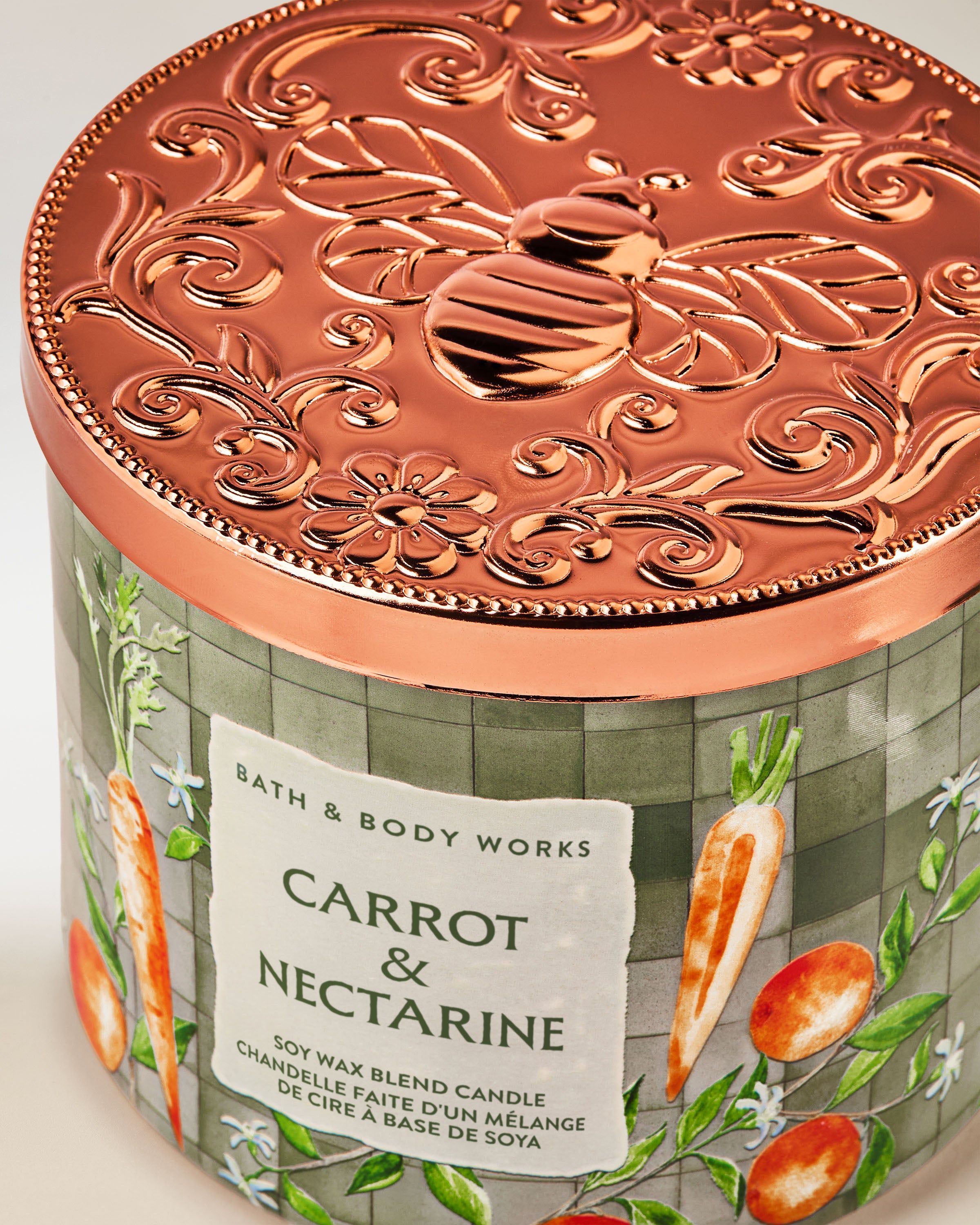 Tříknotová vonná svíčka Bath & Body Works Carrot & Nectarine ve skleněné dóze s rostlinným motivem.