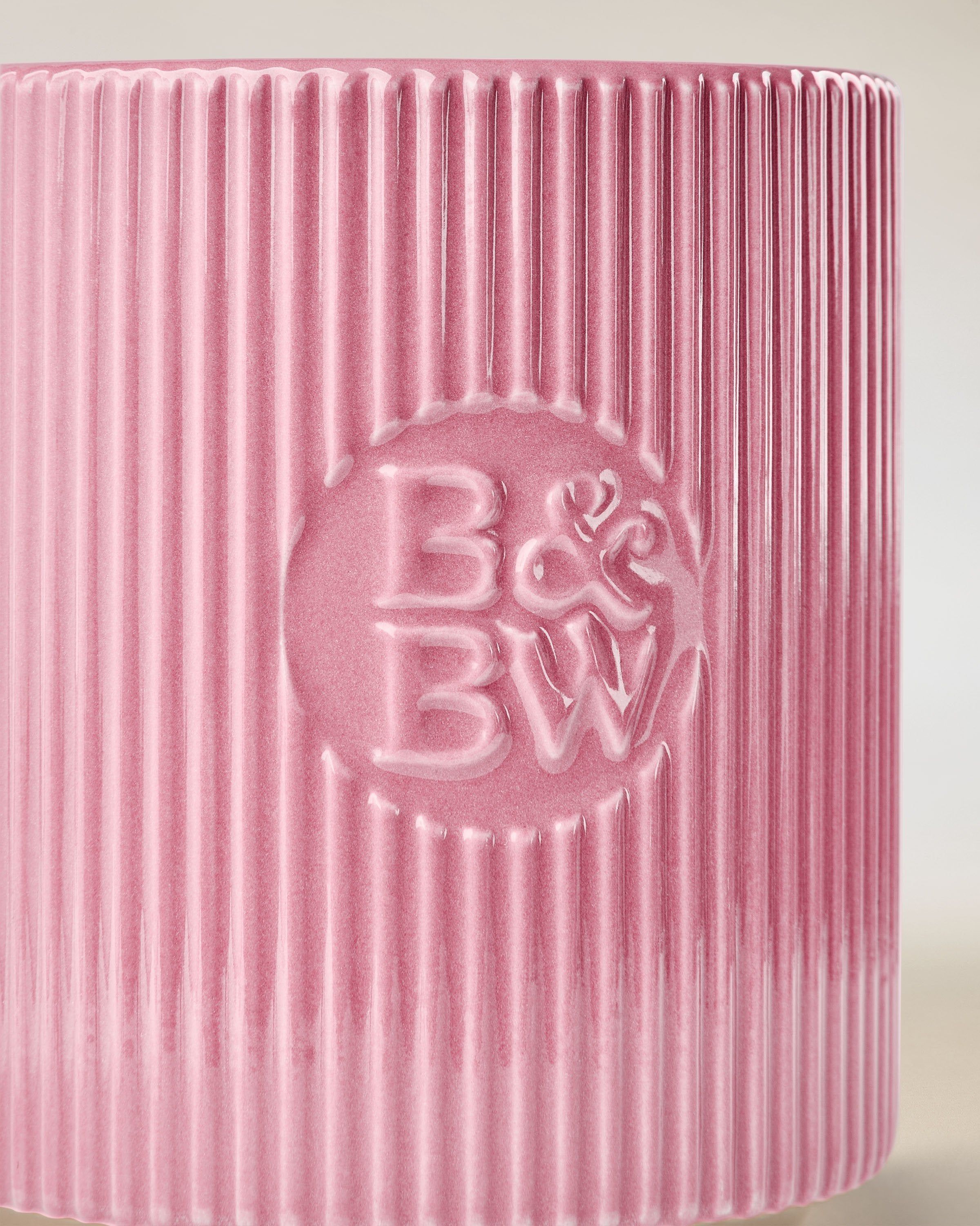 Svíčka Bath & Body Works v růžovém keramickém držáku s rýhovaným povrchem.