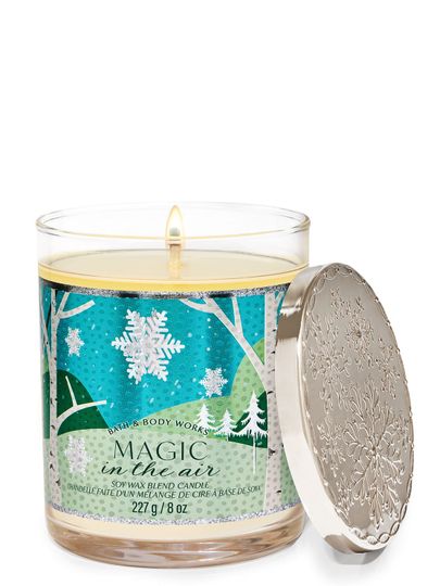Świeca zapachowa „Magic in the Air” z etykietą przedstawiającą zimowy las i duże płatki śniegu, Bath & Body Works.