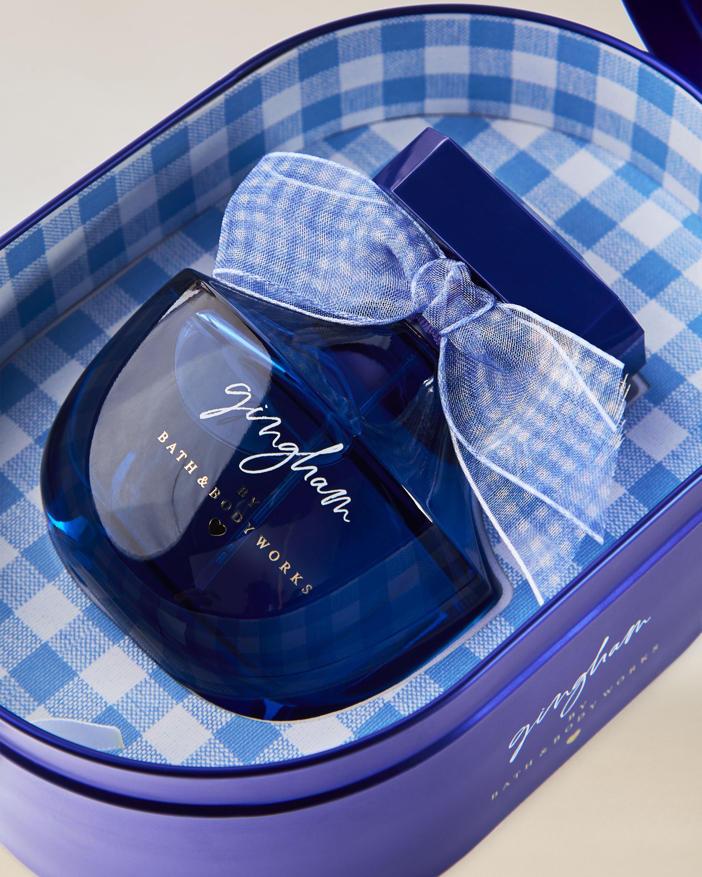 Parfém Bath & Body Works Gingham v modrém skleněném flakonu s dekorativní mašlí.