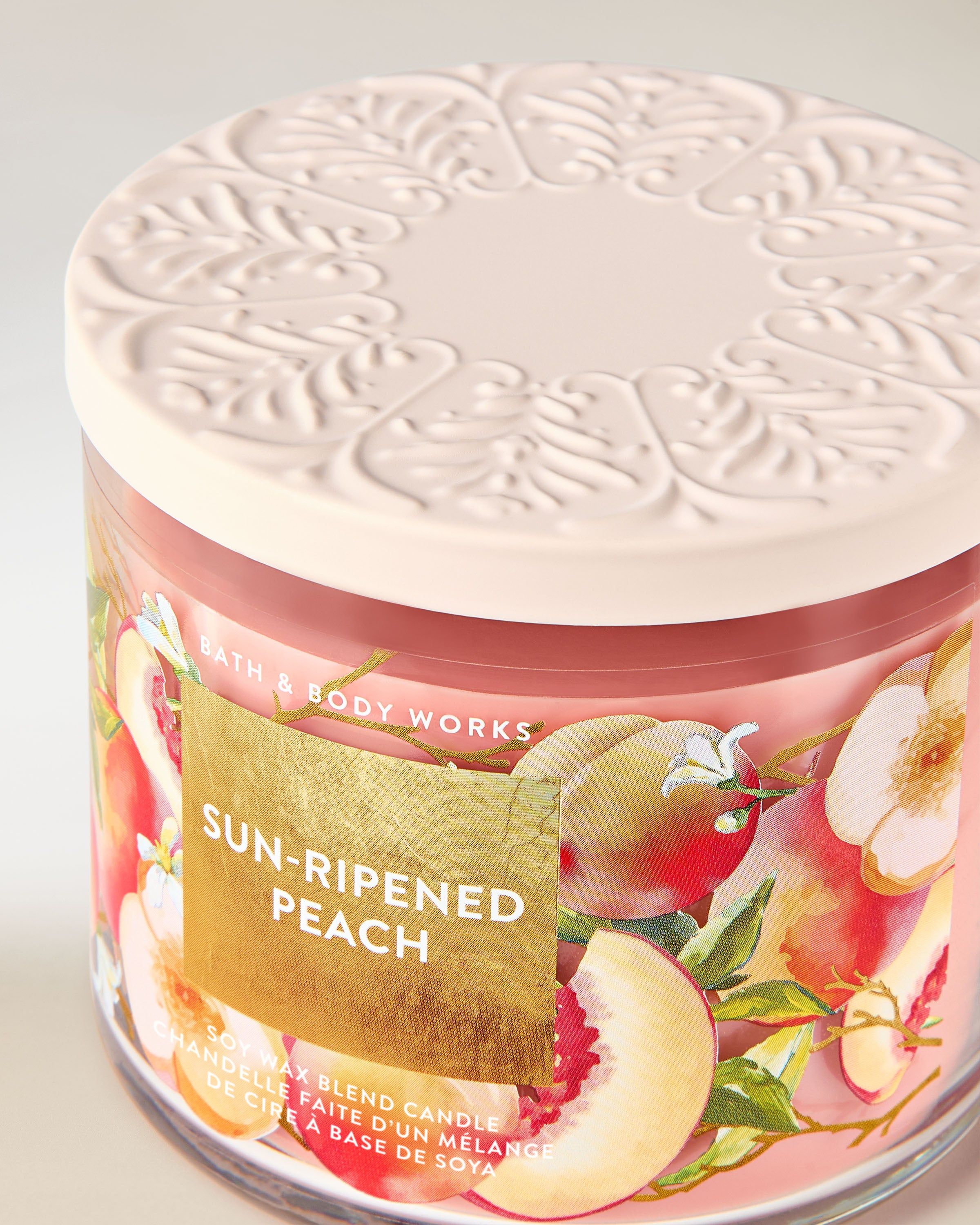 Bath & Body Works Sun‑Ripened Peach – svíčka se světlým reliéfním víčkem a motivem zralých broskví