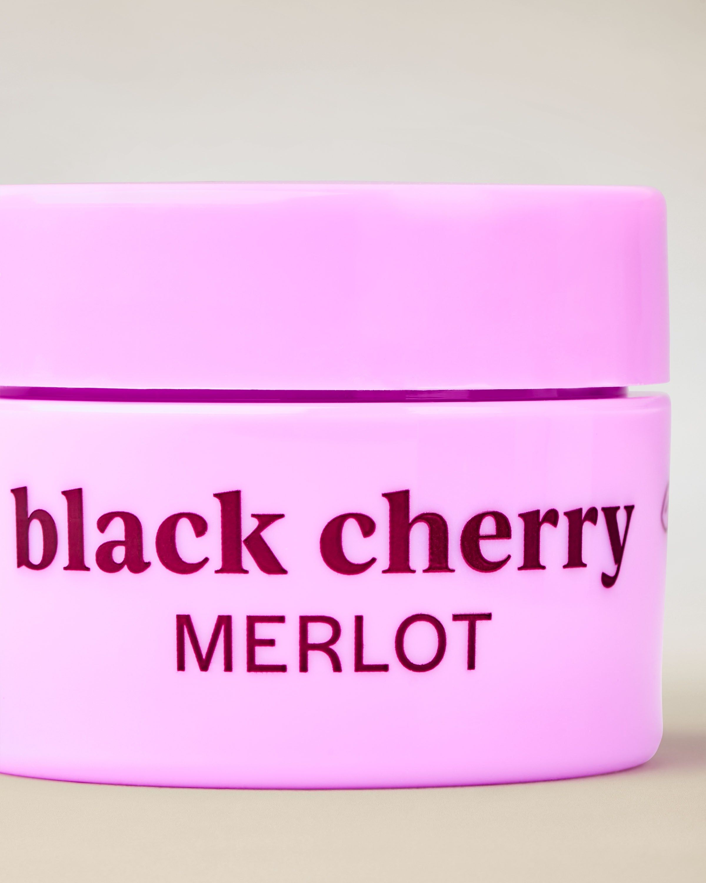 Black Cherry Merlot v růžové dóze s tmavou třešňovou barvou, ideální pro péči o rty.