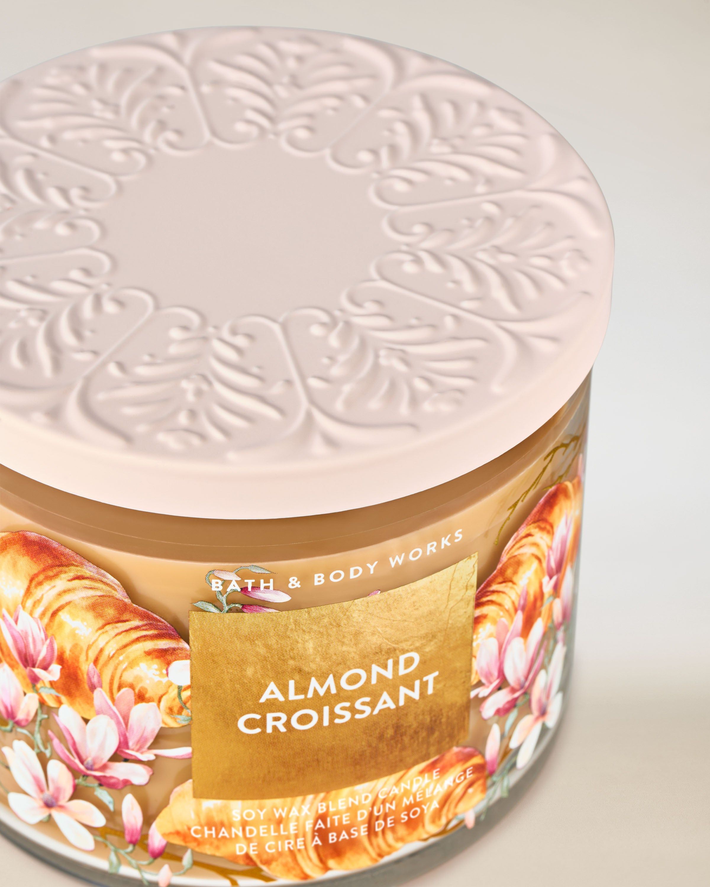 Bath & Body Works Almond Croissant – svíčka se světlým reliéfním víčkem a motivem croissantů a květů