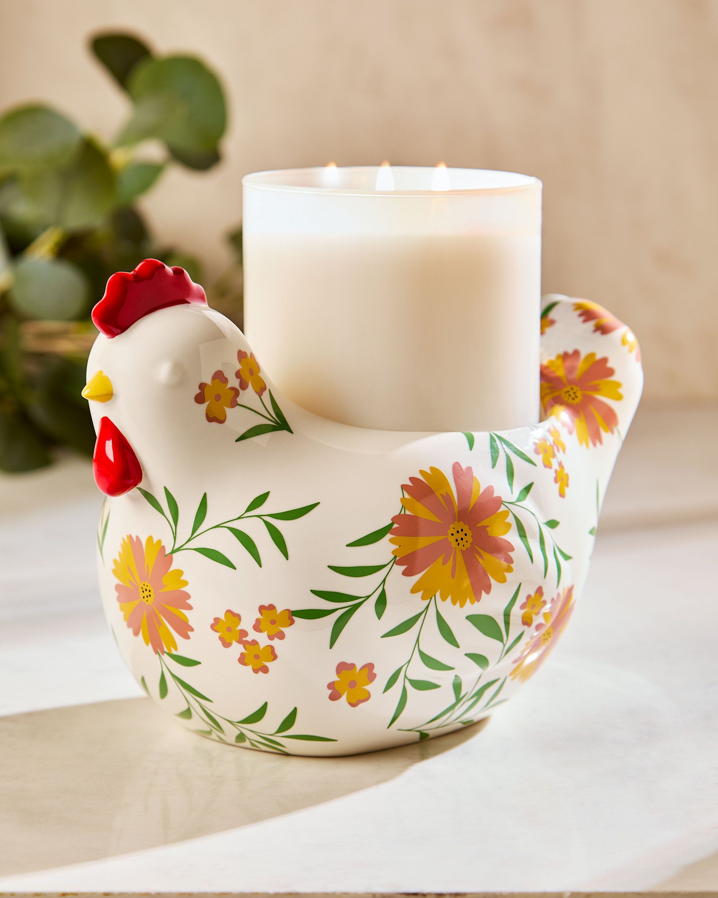 Dekorativní podstavec na tříknotovou svíčku Bath & Body Works ve tvaru slepice s květinovým vzorem.
