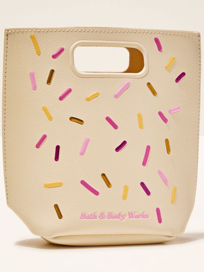 Bath & Body Works – krémová dárková taška s barevnými „sprinkles” detaily a výřezem na uchopení.