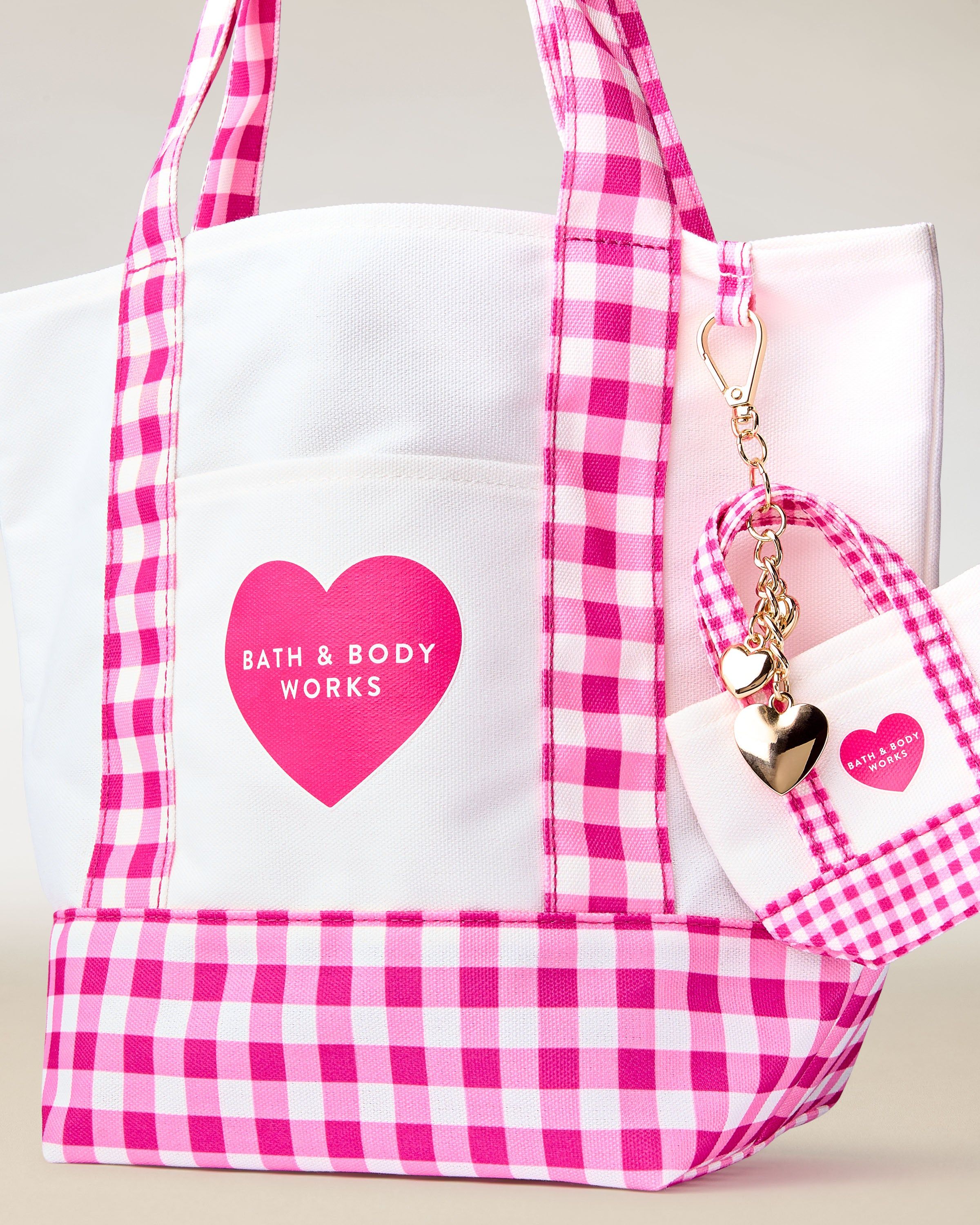 Taška Bath & Body Works s růžovo‑bílým gingham vzorem, uchy a ozdobným přívěskem.