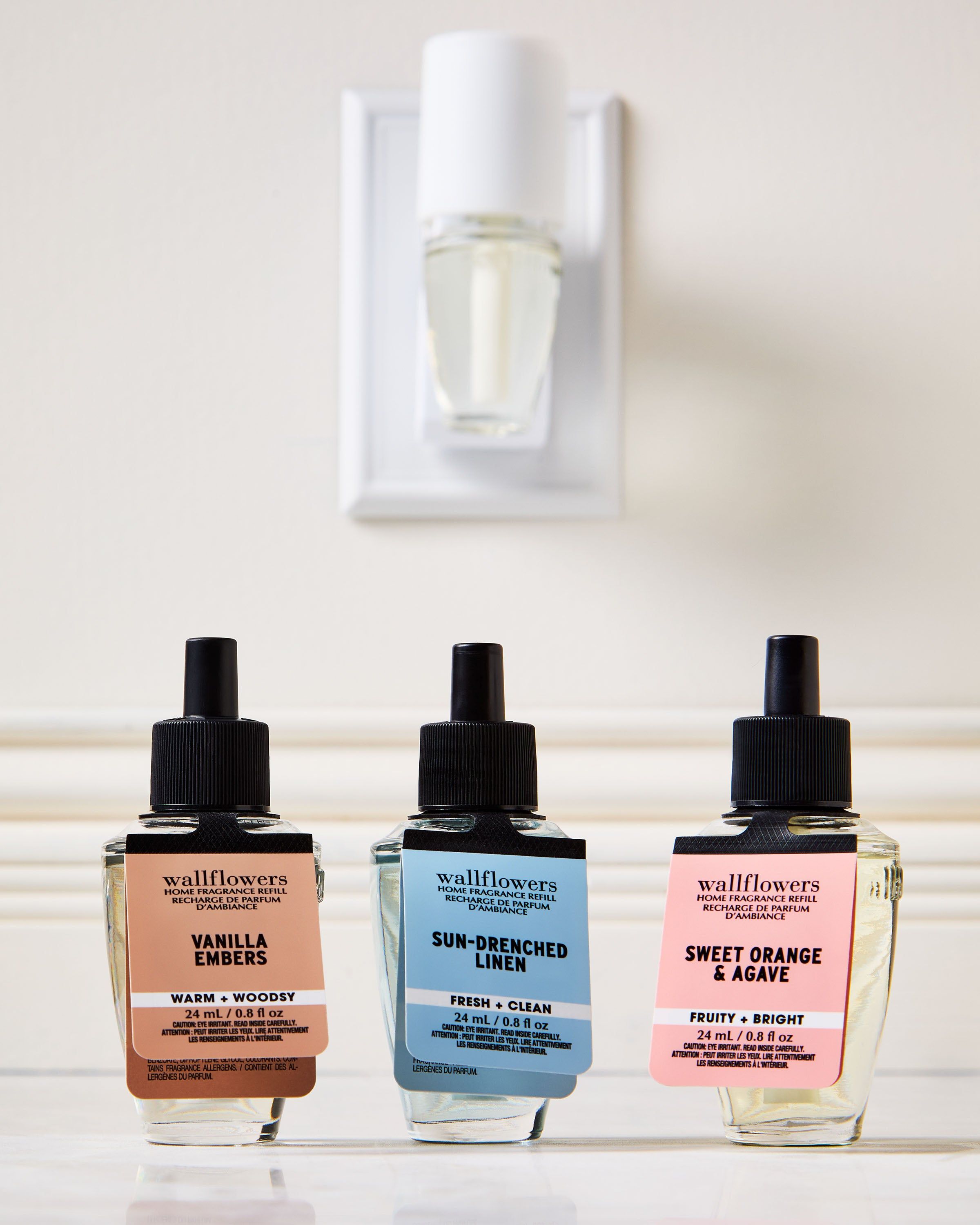 Sada náplní Wallflowers: Vanilla Embers, Sun‑Drenched Linen a Sweet Orange & Agave ve skleněných lahvičkách.
