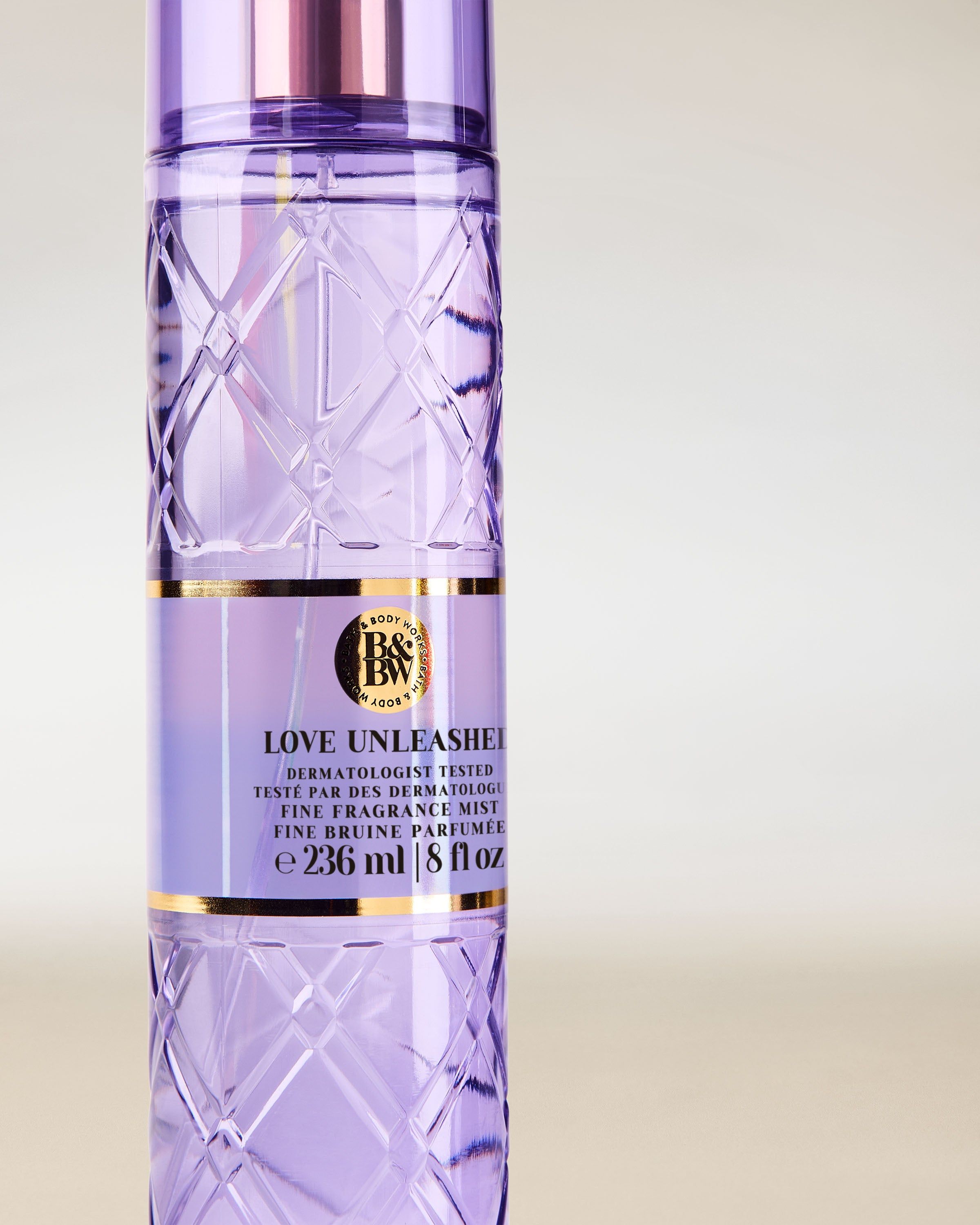 Bath & Body Works Love Unleashed – lila voňavá mlha v reliéfní lahvi s růžovo‑zlatým rozprašovačem.