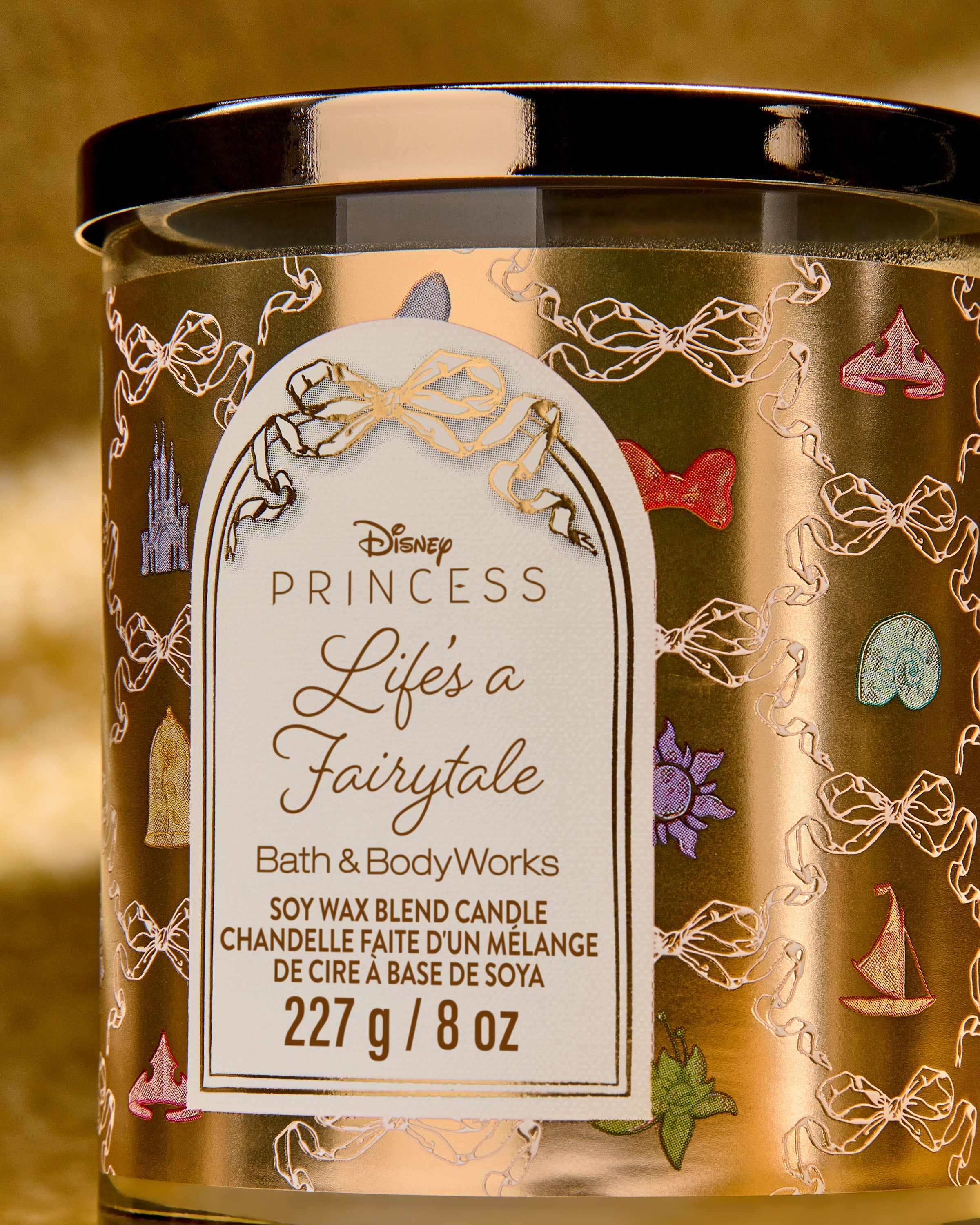 Svíčka Life’s a Fairytale z kolekce Disney Princess ve zlatém designu s pohádkovými ikonami.