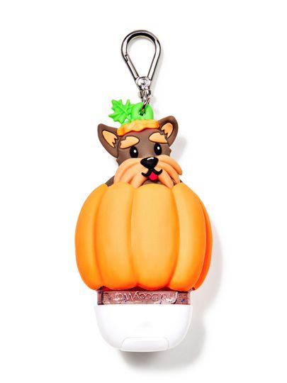 Pouzdro na gel na ruce Bath&Body Works ve tvaru psa v dýni. Oranžové pouzdro s hnědým psem a kovovou karabinou.