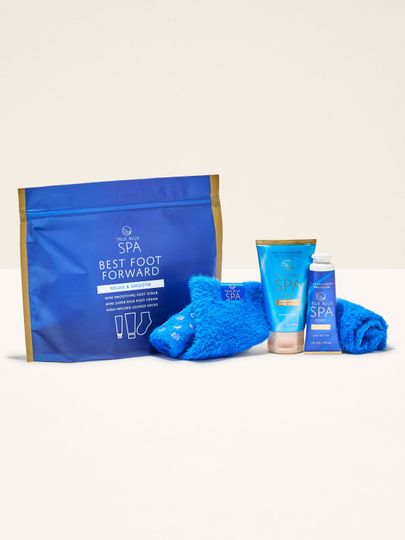 Sada True Blue Spa Best Foot Forward v modrém sáčku: krém na nohy, peeling a ponožky s bambuckým máslem.