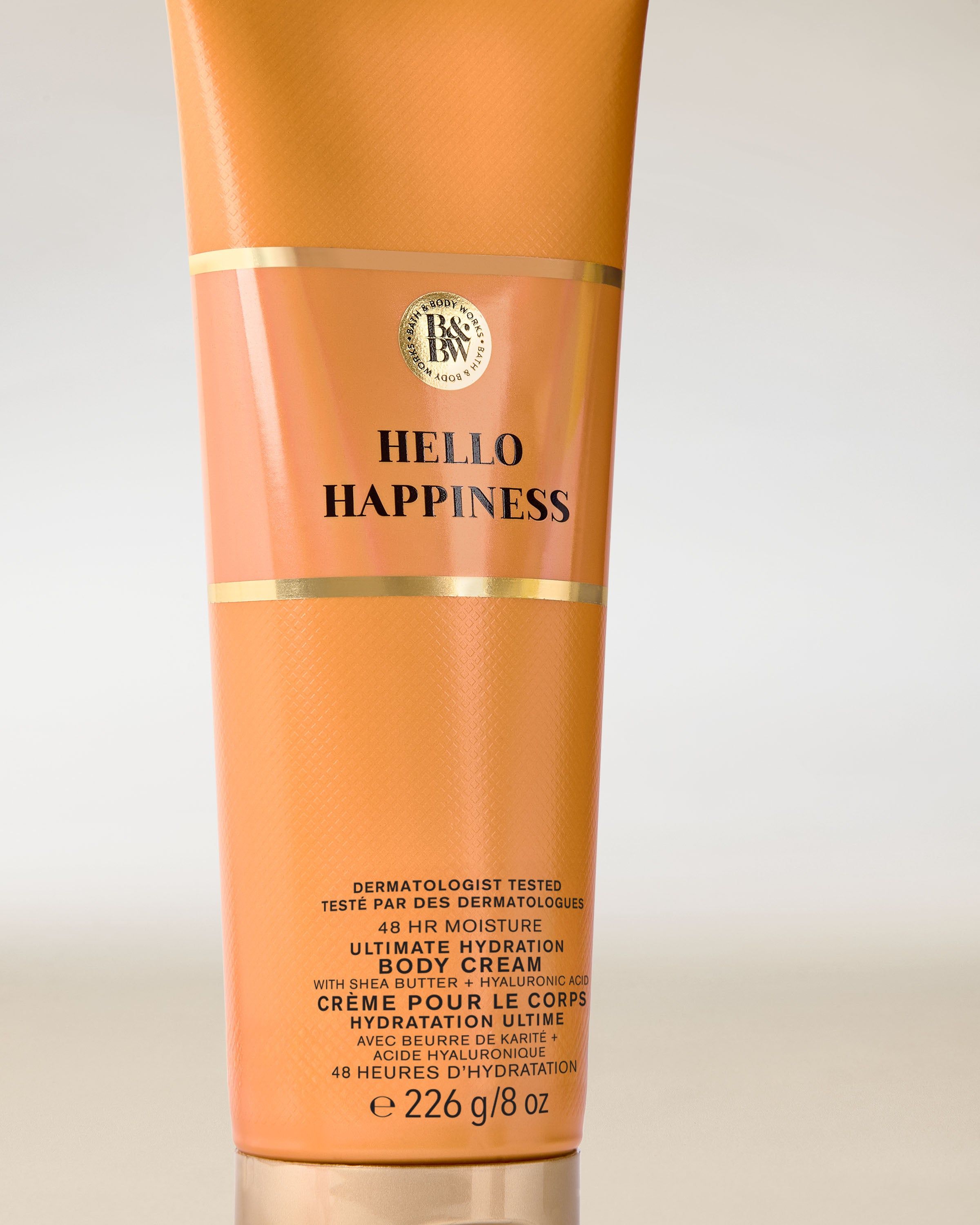 Tělový krém Hello Happiness Bath & Body Works v oranžové tubě se zlatými prvky – plný energie.
