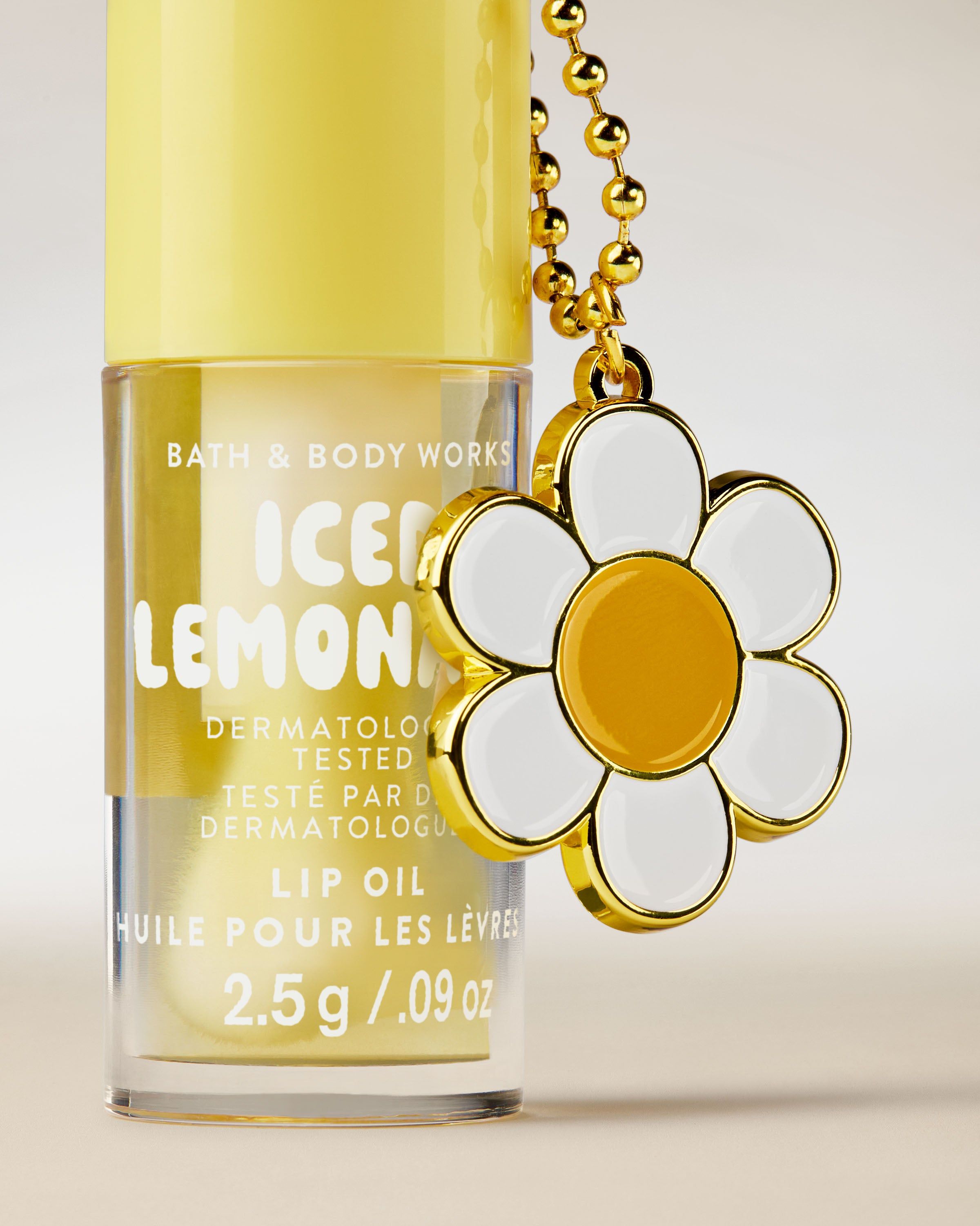 Olej na rty Bath & Body Works Iced Lemonade 2,5 g ve žlutém obalu s ozdobným přívěskem.