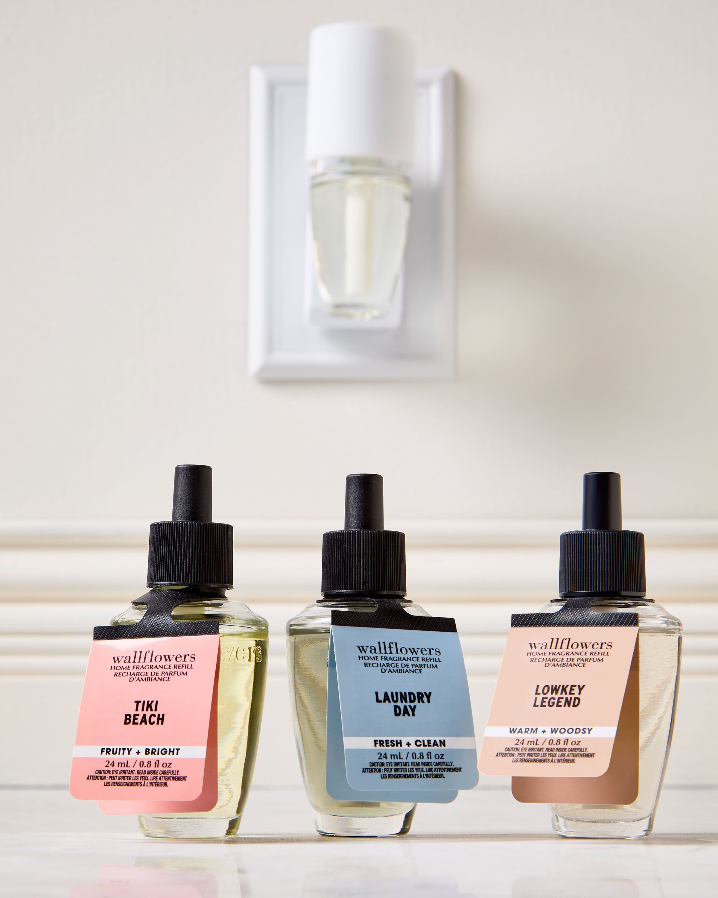 Trojice náplní Wallflowers: Tiki Beach, Laundry Day a Lowkey Legend před nástěnným difuzérem.