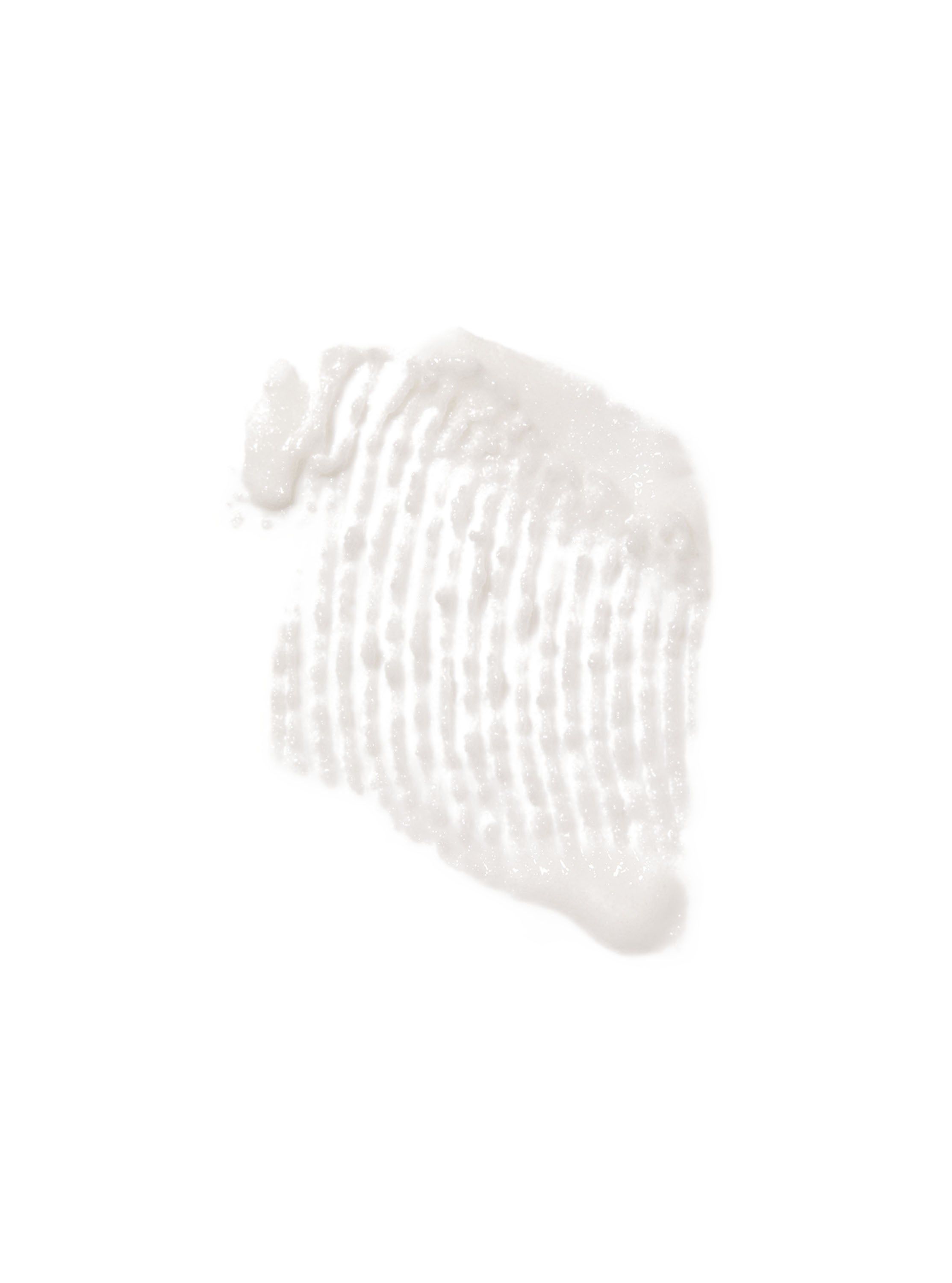 Swatch peelingu (exfoliačního krému) rozmazaný na bílém pozadí. Viditelné granule a krémová textura.