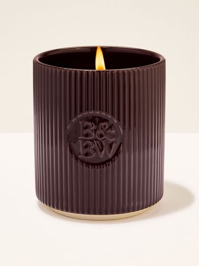 Svíčka Bath & Body Works v tmavě hnědém keramickém držáku s rýhovaným povrchem.