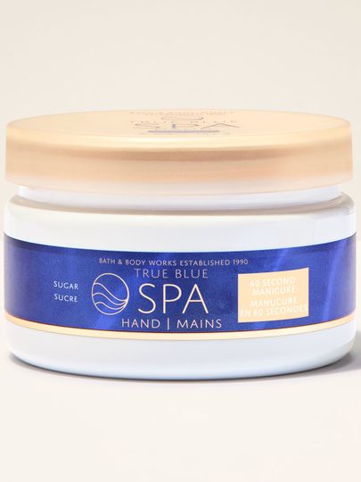 Peeling na ruce Bath&Body Works True Blue Spa. Bílý kelímek se zlatým víčkem a modrou etiketou s nápisy.