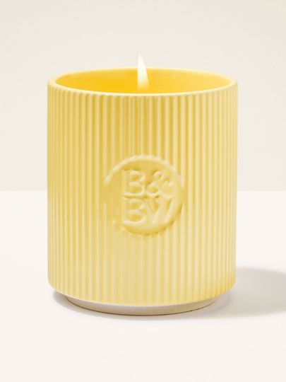 Svíčka Bath & Body Works v žlutém keramickém držáku s rýhovaným povrchem.