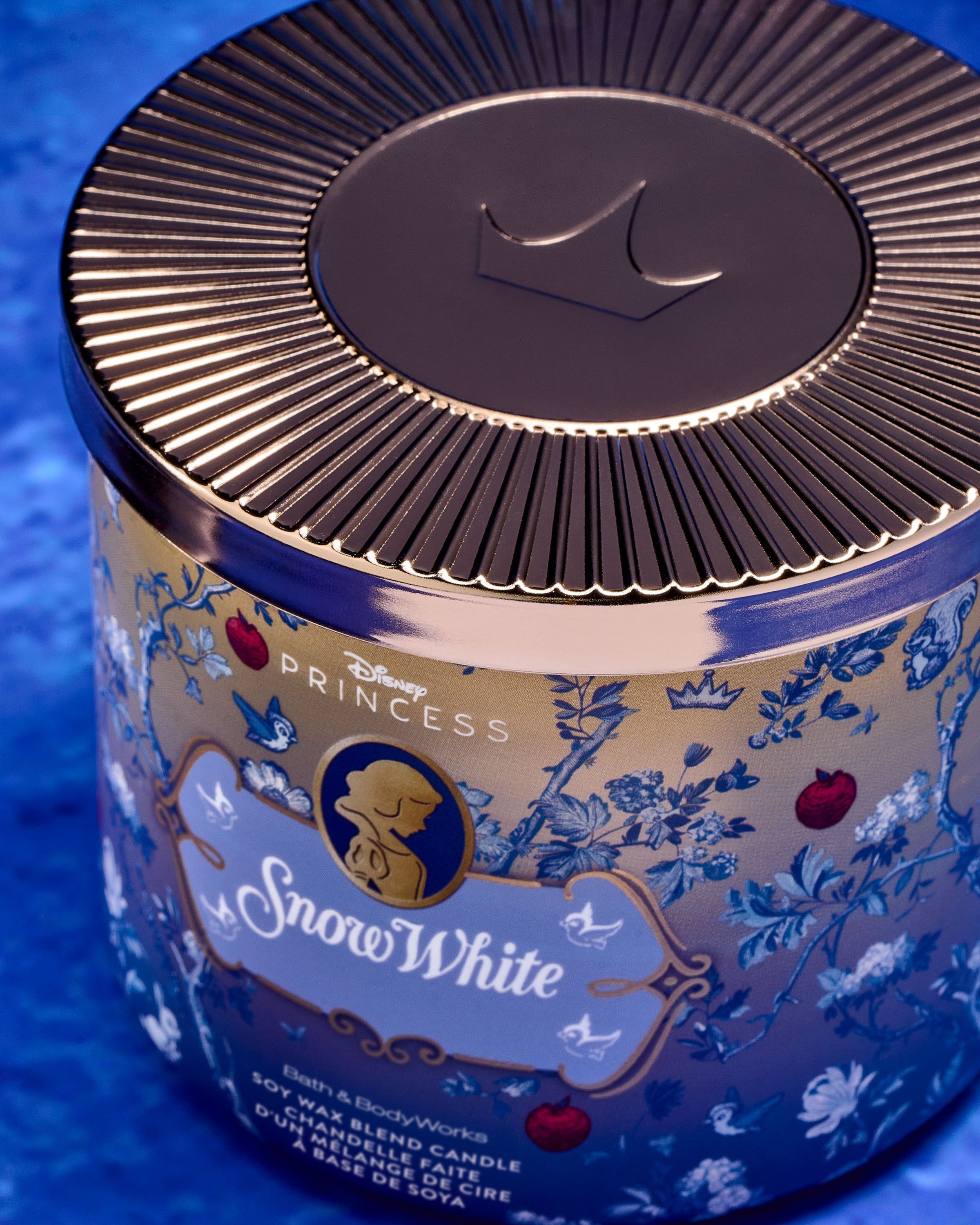 Tříknotová svíčka Snow White ve zlatomodrém designu s jablky, ptáčky a královskými detaily.