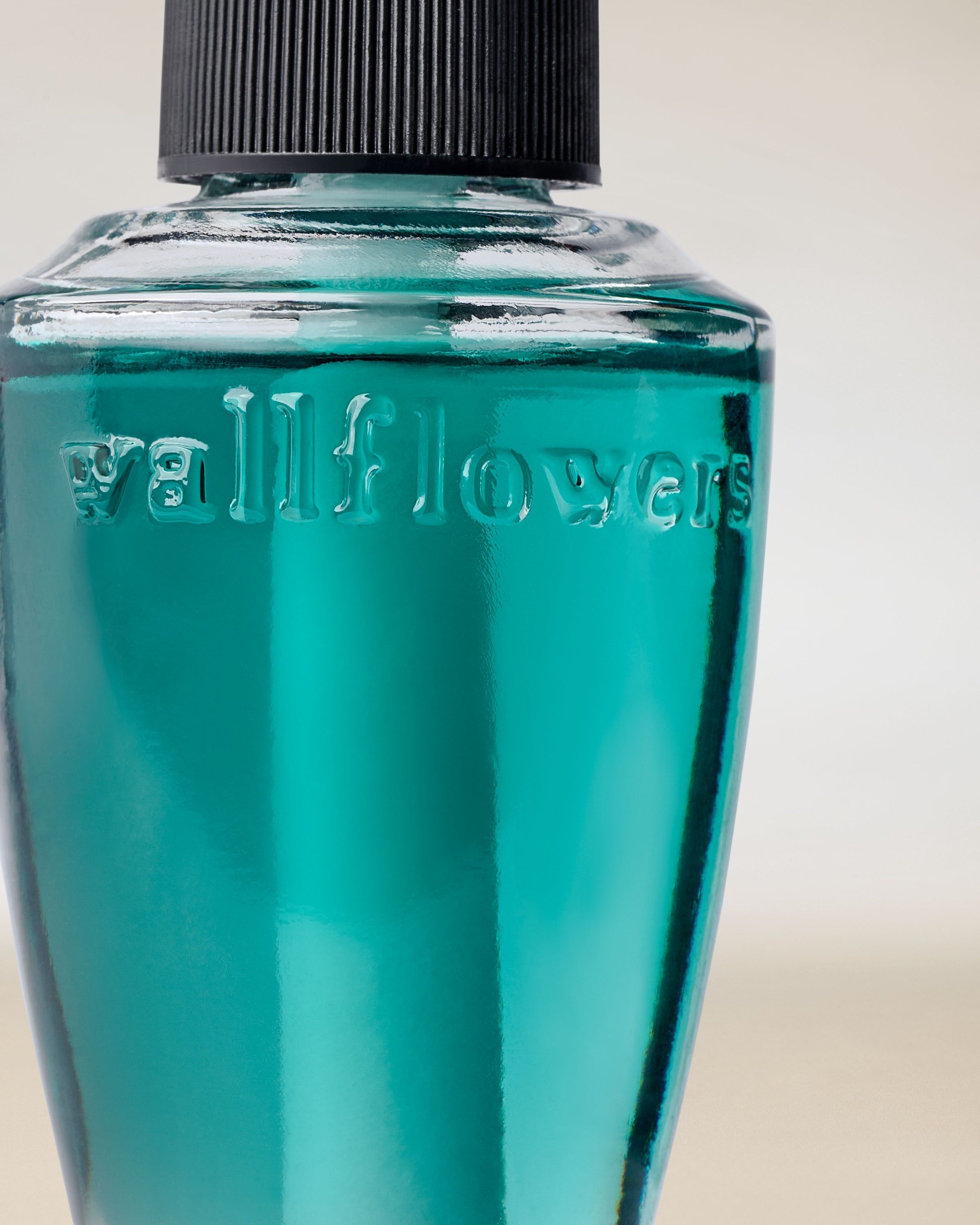 Detail skleněné lahvičky náplně Wallflowers se zvýrazněným reliéfním logem a barvou vonné esence.