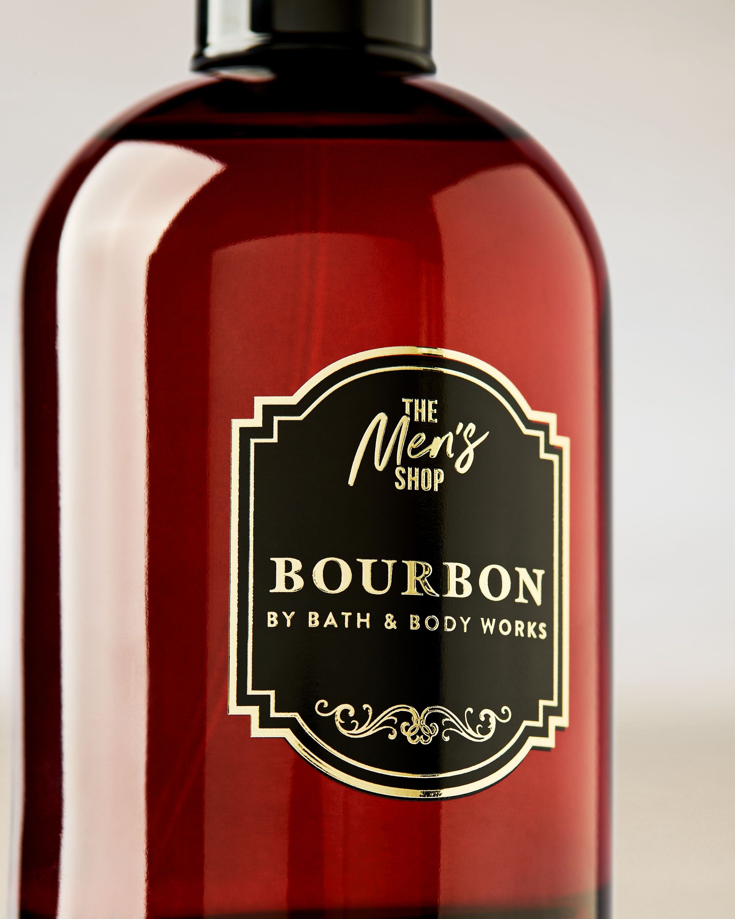 Bath & Body Works Bourbon – tmavě červený flakon s černým uzávěrem a dekorativním štítkem ve stylu Men’s Shop.