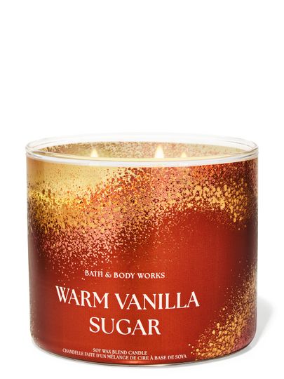 Zapálená svíčka se třemi knoty Bath & Body Works "Warm Vanilla Sugar" ve zlato-oranžové nádobě s třpytkami.