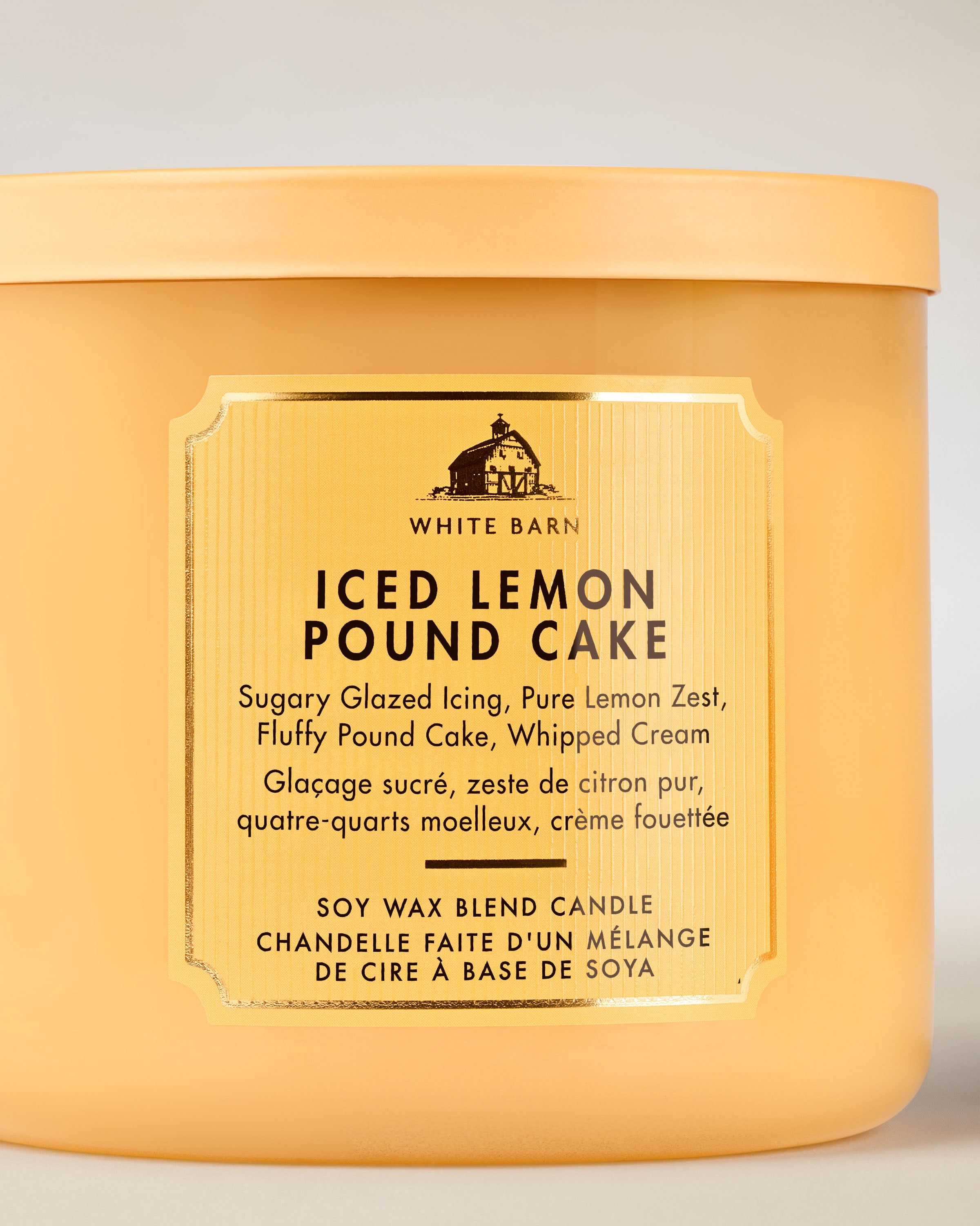 Tříknotová vonná svíčka White Barn Iced Lemon Pound Cake v matné žluté skleněné dóze.