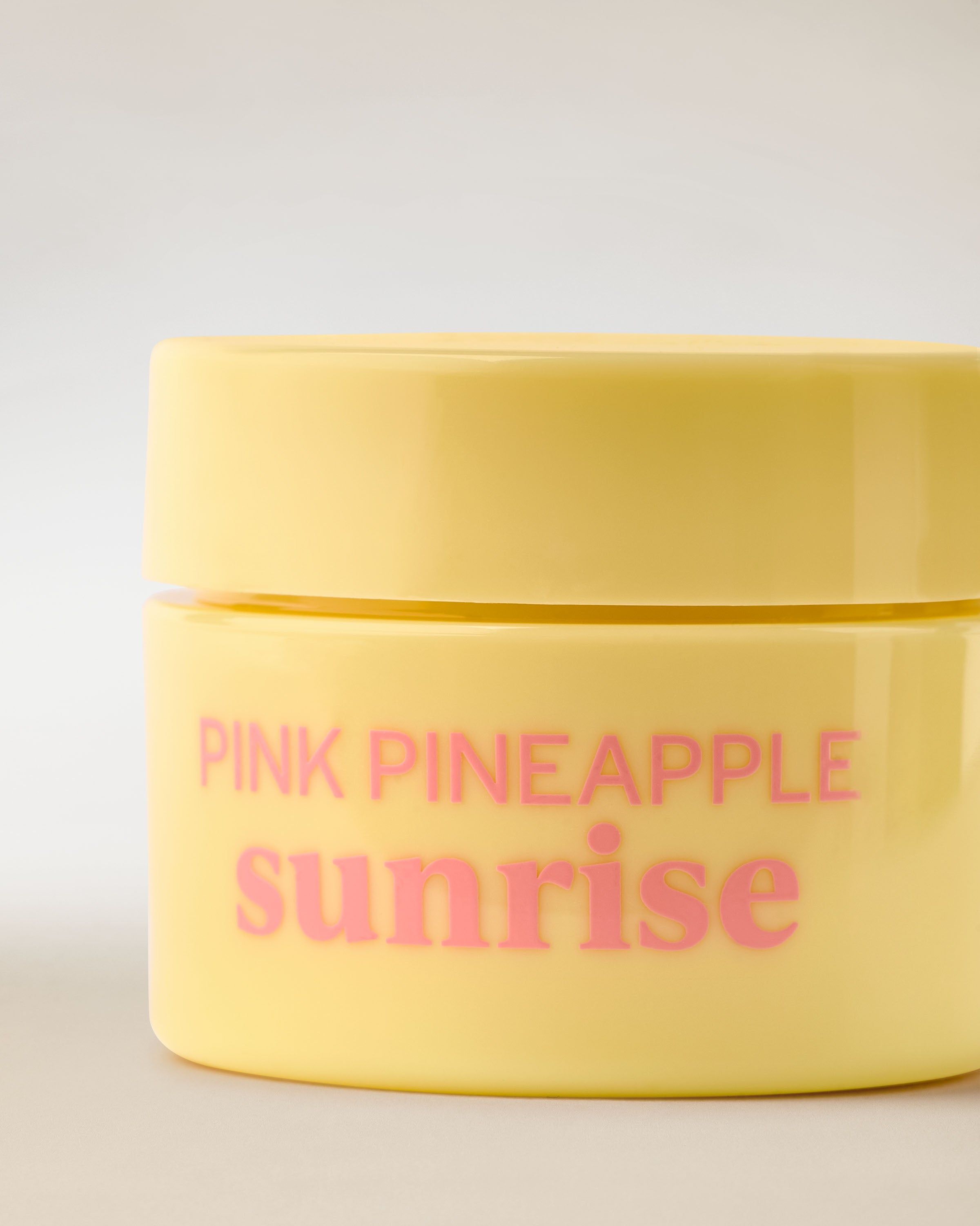 Žlutá dóza Nourishing Lip Mask s růžovou etiketou a ananasovým motivem v čistém produktovém záběru.