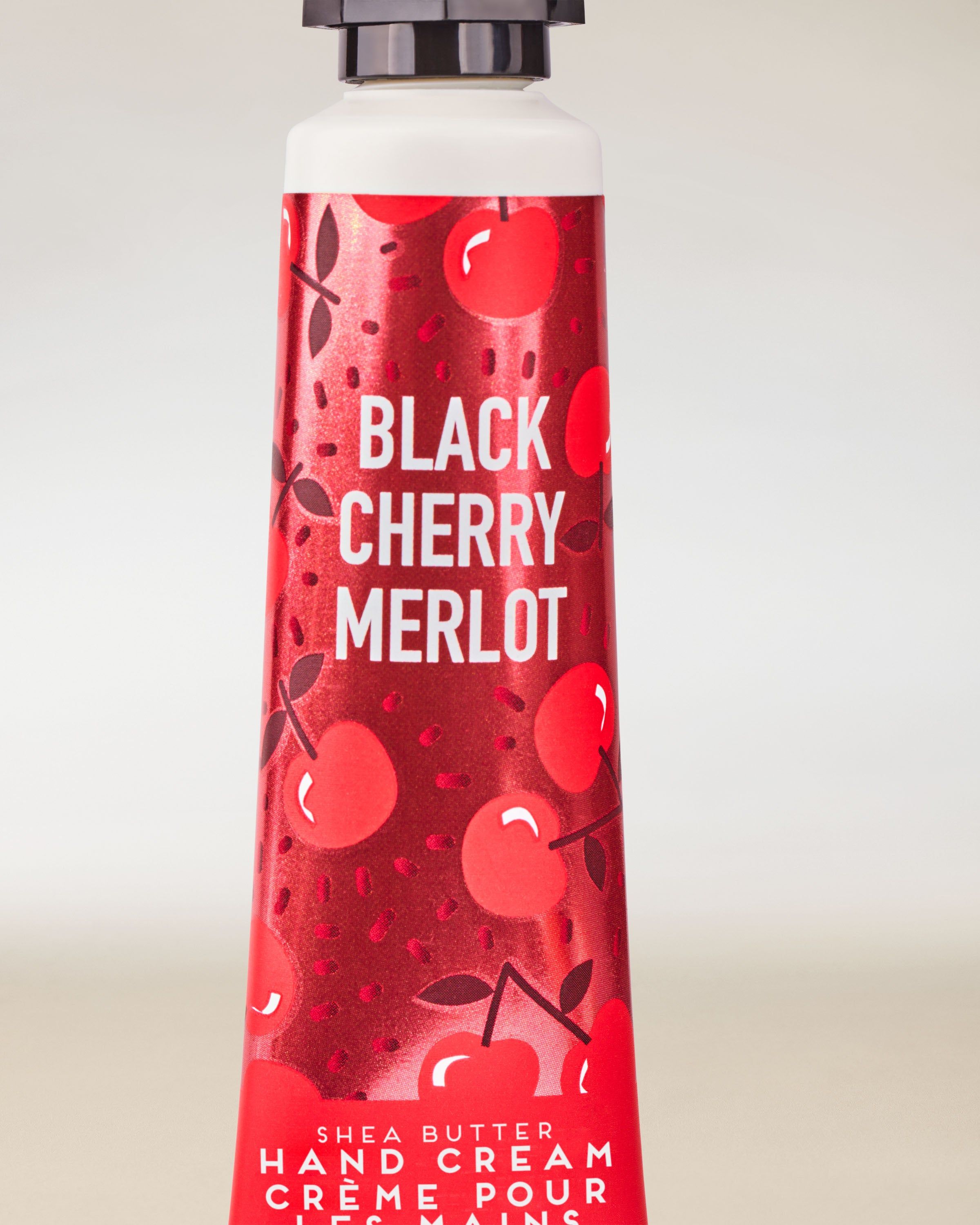 Krém na ruce Black Cherry Merlot od Bath & Body Works v červené tubě s dekorativní třešňovou grafikou.