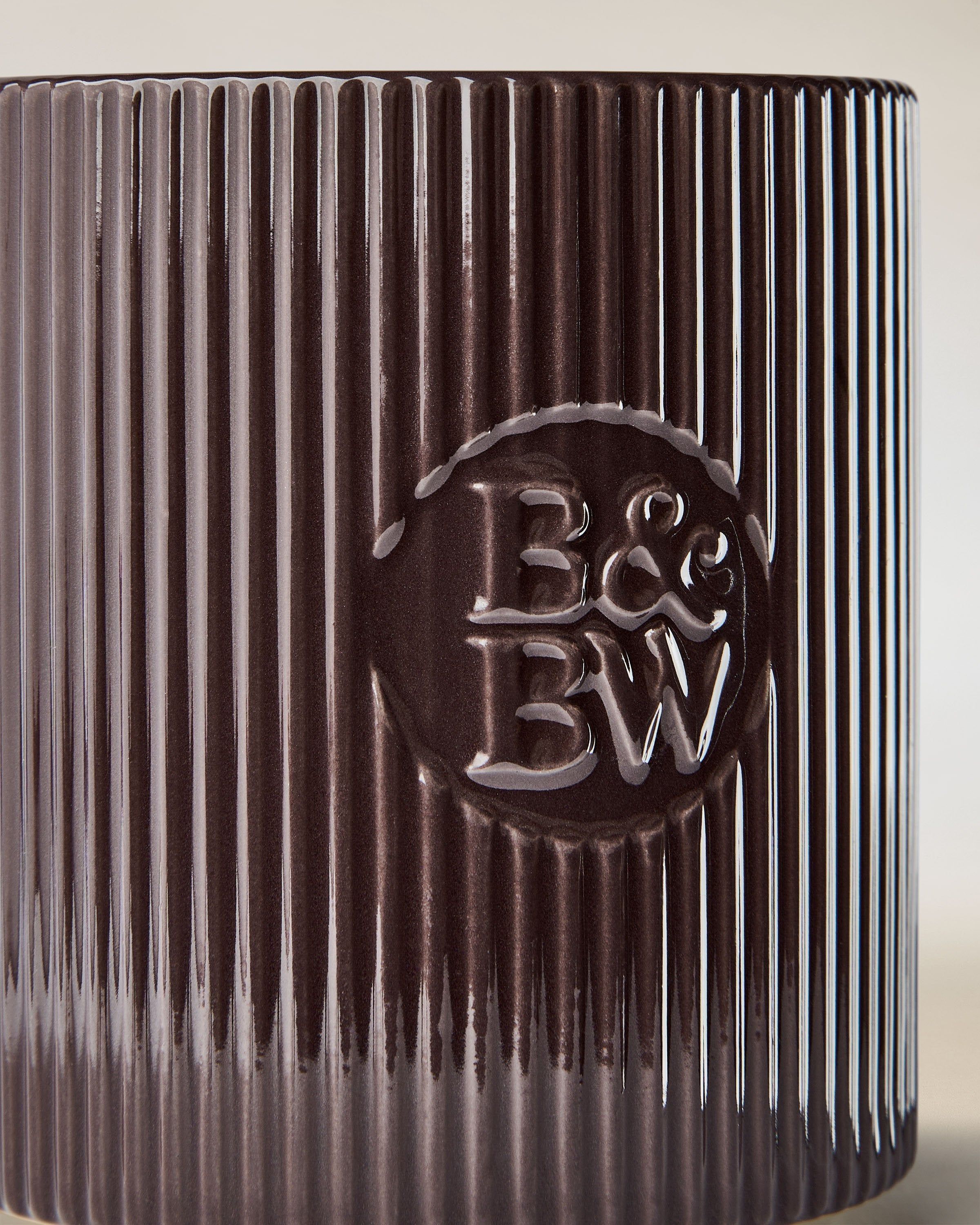 Svíčka Bath & Body Works v tmavě hnědém keramickém držáku s rýhovaným povrchem.