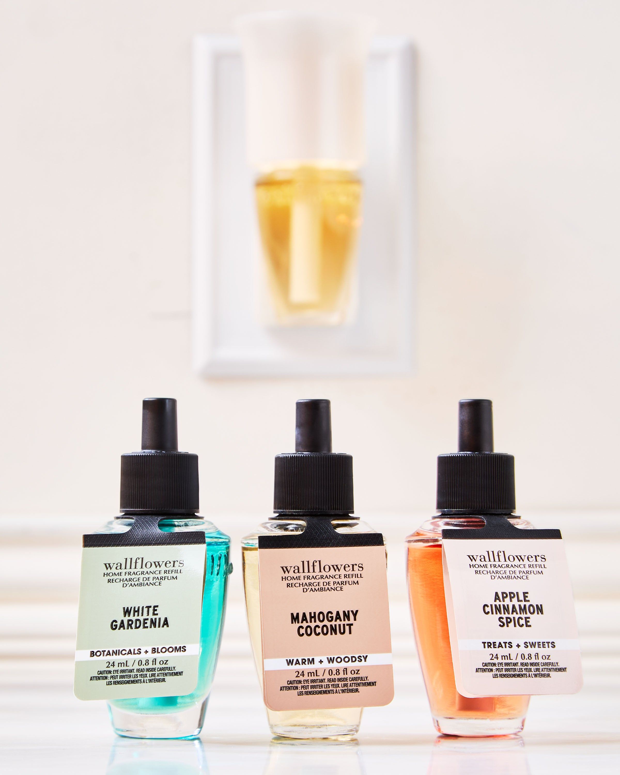 Sada náplní Wallflowers: White Gardenia, Mahogany Coconut a Apple Cinnamon Spice ve skleněných lahvičkách.