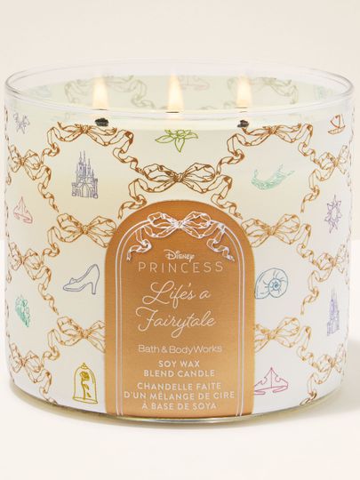 Tříknotová svíčka Life’s a Fairytale ve světlém designu se symboly princezen a zlatými detaily.
