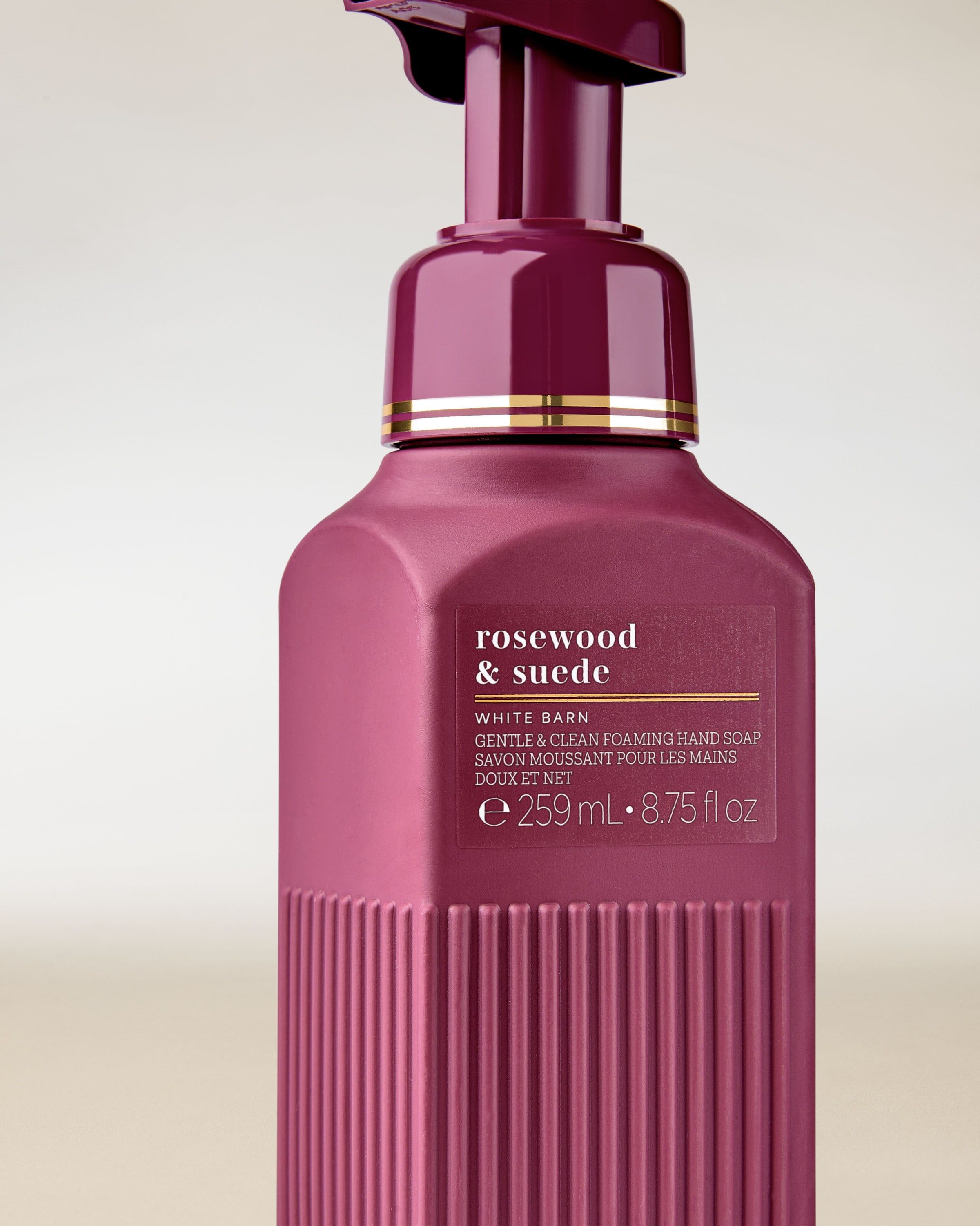 Detail pěnového mýdla „Rosewood & Suede“ v elegantní láhvi v tmavě bordó odstínu.